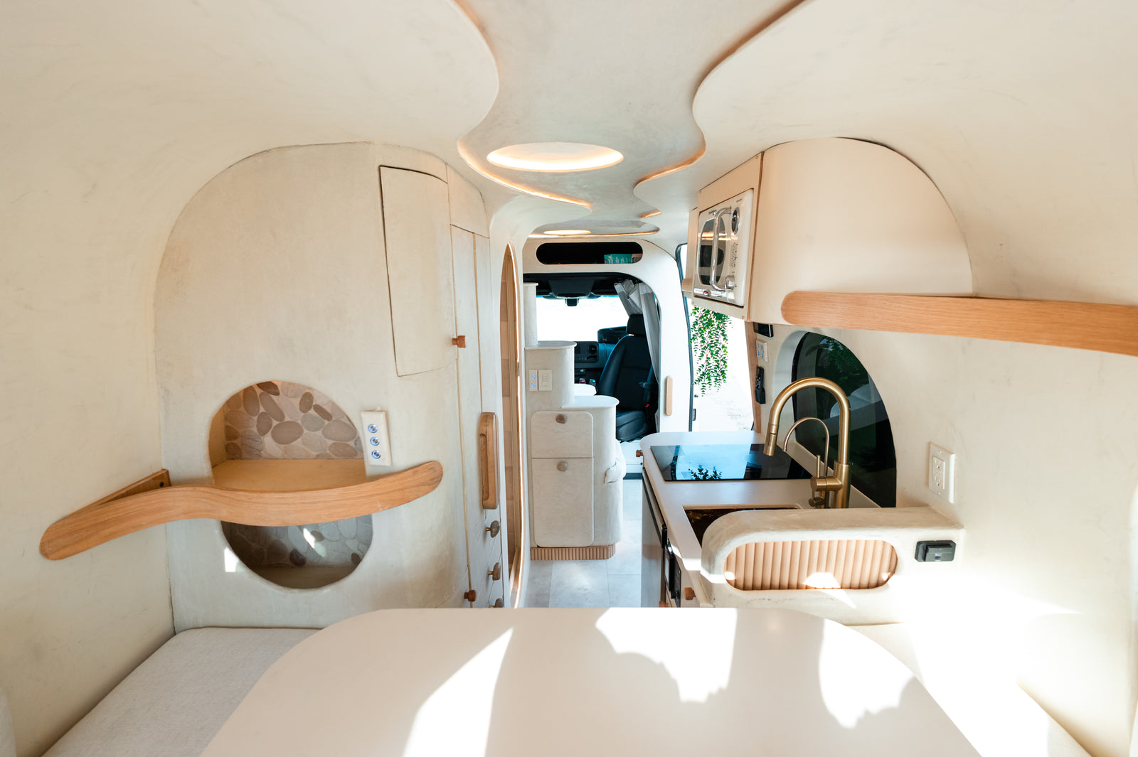 Flow's galley viewed from the rear dinette toward the cab, showing the curved cabinetry and ceiling lights