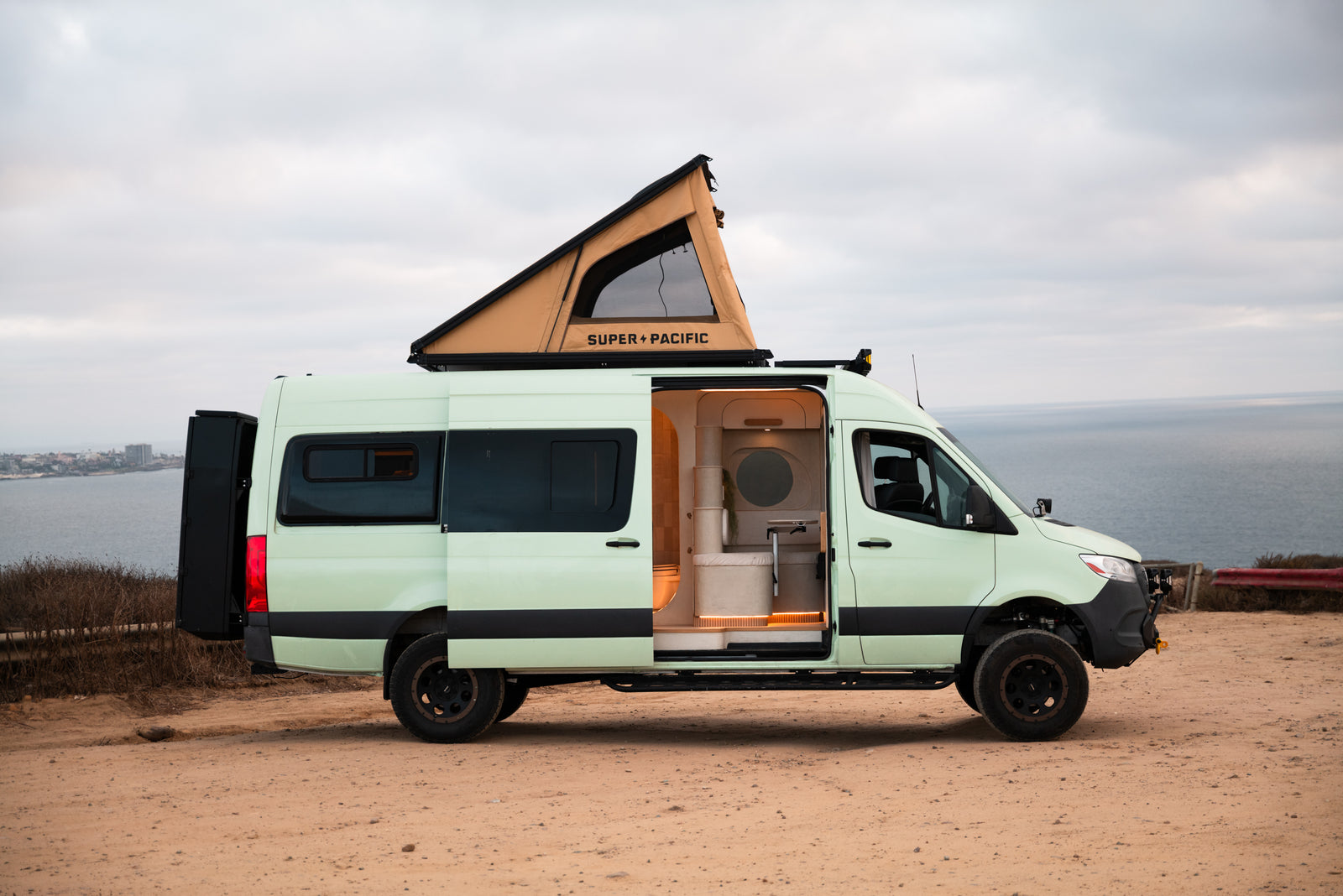 Flow in side profile above the coast with its rooftop tent and side door open
