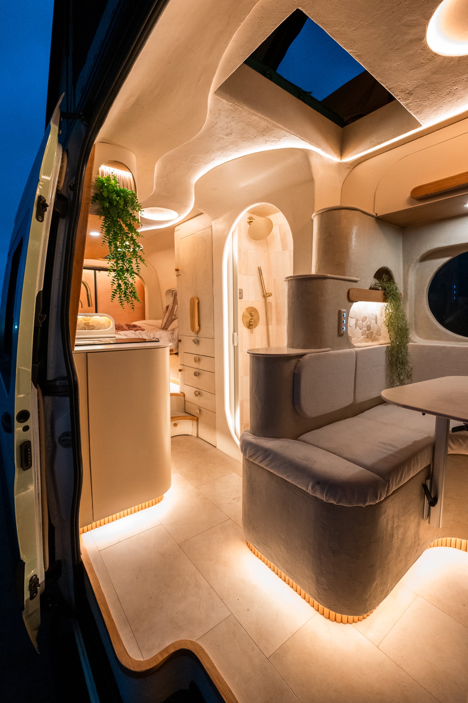Flow's dinette, shower, galley, and pop-top opening illuminated at blue hour
