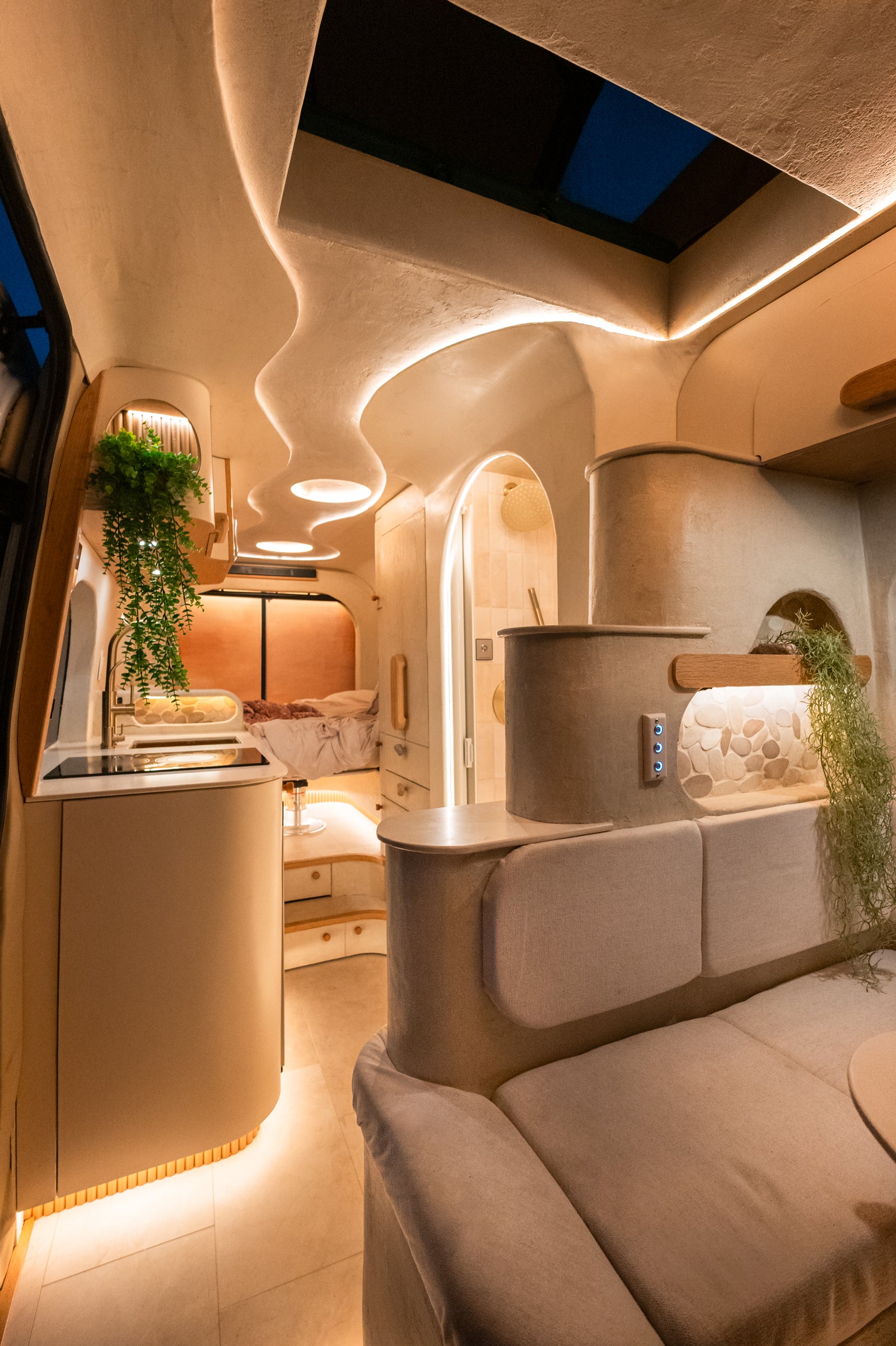 Flow's dinette, galley, shower, and made-up bed under warm evening lighting