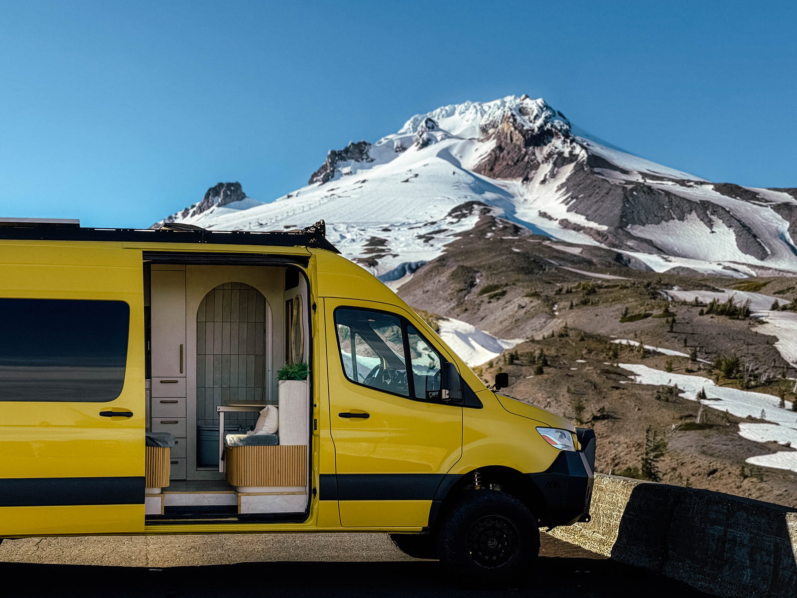 The Luna van parked below a snow-capped mountain