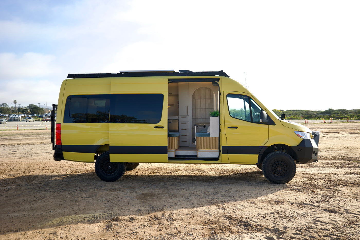 Side profile of the Luna, a yellow 4x4 Sprinter with roof rack and open slider door